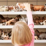little blond girl reaching for a cow toy