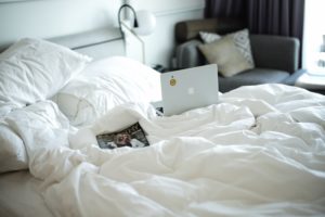 unmade bed with a computer on it