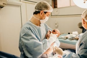 man holding a baby after a cesarean section delivery