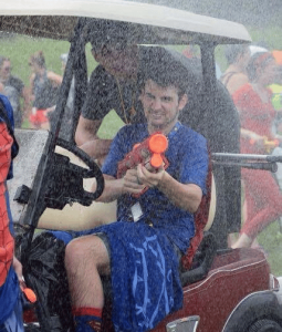 boy shooting a water gun from a golf cart