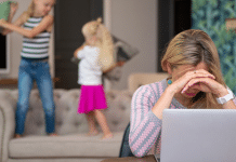 Mom trying to work on her laptop while her kids jump behind her.