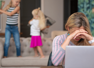 Mom trying to work on her laptop while her kids jump behind her.