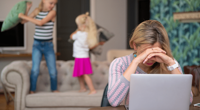 Mom trying to work on her laptop while her kids jump behind her.