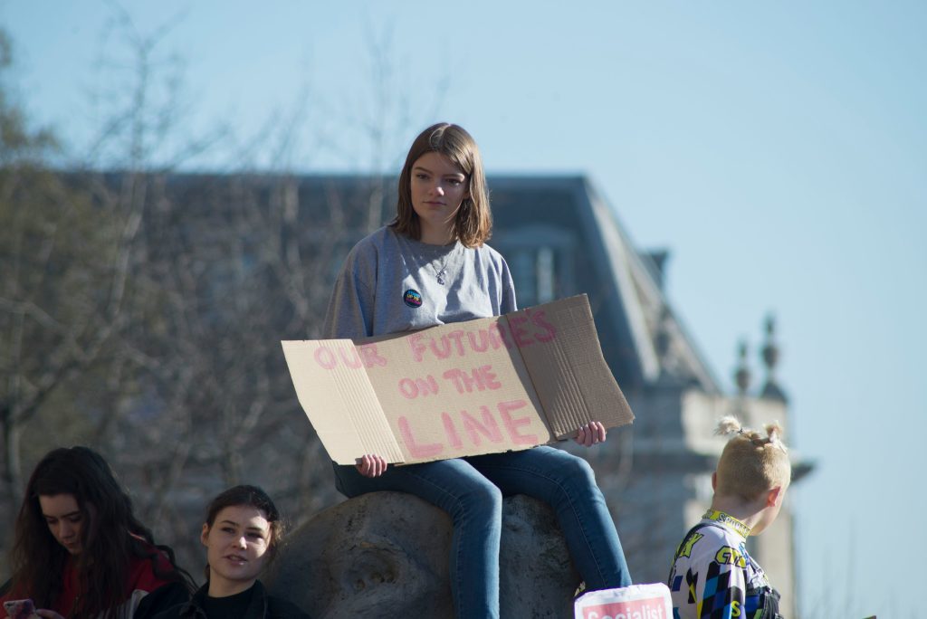 Teen with a protest sign that says "Our futures are on the LINE"