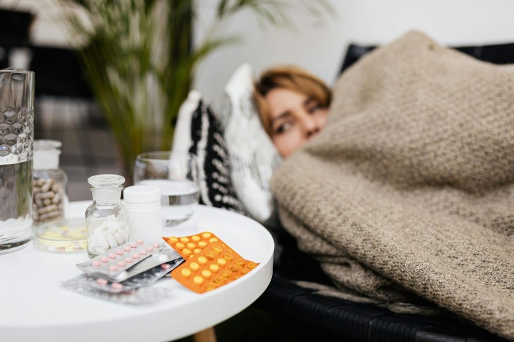woman lying on the couch looking at piles of pills