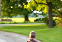 Letting Go of Teens: What School Drop Offs Teach You little boy with a red backpack walking down the driveway to meet the bus