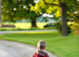 Letting Go of Teens: What School Drop Offs Teach You little boy with a red backpack walking down the driveway to meet the bus
